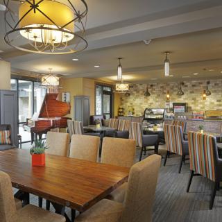 A cozy dining area with warm lighting, featuring wooden tables and upholstered chairs.