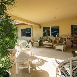 A cozy patio with wicker furniture and lush plants under a covered area.