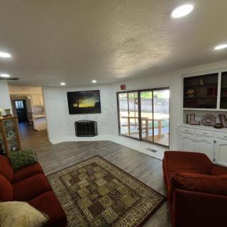 A cozy living room with a flat-screen TV, comfortable sofas, and large windows.