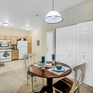 A cozy dining area with a round table set for two, adjacent to an open kitchen.