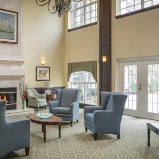 A cozy living room with armchairs, a fireplace, and large windows.