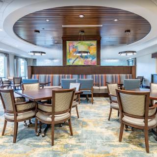 A modern dining area with elegantly arranged tables and chairs, featuring stylish lighting and vibrant artwork.