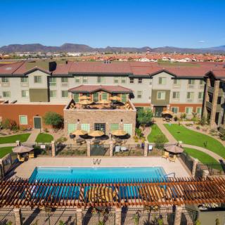 Aerial view of a hotel with a swimming pool set amidst landscaped gardens.