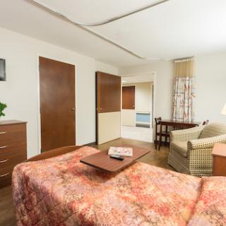A cozy and inviting bedroom featuring a comfortable bed, seating area, and modern decor.
