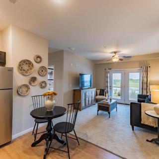 A cozy open-plan living and dining area with modern decor, featuring a small dining table, television, and tasteful wall art.