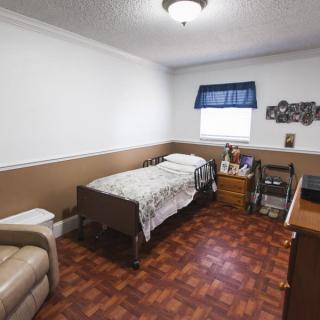 A cozy bedroom with a single bed, wooden flooring, and simple furnishings.