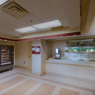 A quiet cafeteria interior with a vending machine and food service counter.