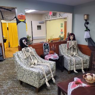 A playful Halloween decoration featuring skeletons sitting in chairs, adding a spooky touch to the living room.