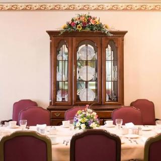 A traditional dining room with a set table and a china cabinet in the background.