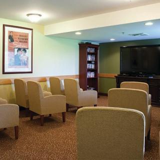 A small meeting room with rows of comfortable chairs facing a large television.