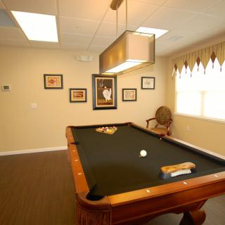 A cozy game room with a pool table and framed artwork on the walls.