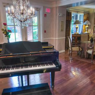 An elegant living room with a grand piano and a sparkling chandelier.