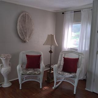 A cozy living room corner with wicker chairs and red cushions.