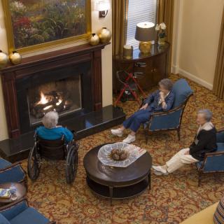 Elderly individuals relaxing by the fireplace in a cozy living room.