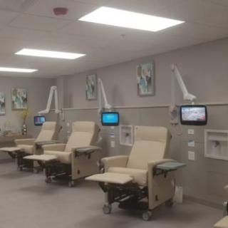 A spacious hospital infusion room with treatment chairs and monitors.