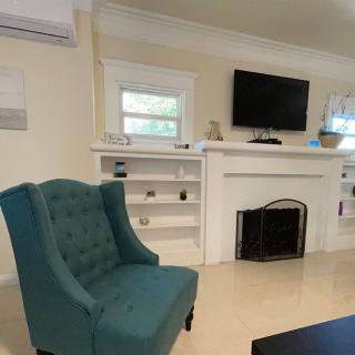 A cozy living room featuring a teal armchair, a fireplace with a TV mounted above, and built-in shelves.