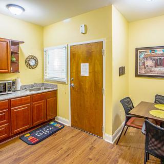 A cozy kitchen and dining area with wooden cabinets, a table set, and wall decorations.