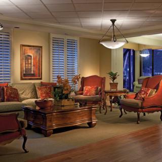 A traditionally styled living room featuring comfortable seating, elegant lighting, and decorative artwork.