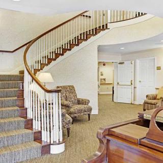 A lobby with a curved staircase and comfortable seating.