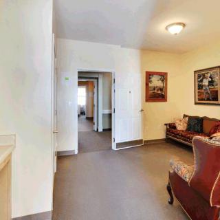 A cozy living room featuring a sofa, artwork on the walls, and an adjoining corridor.