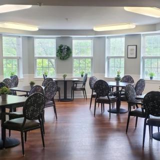 A well-lit dining area with several tables and chairs, featuring large windows that allow natural light to fill the space.