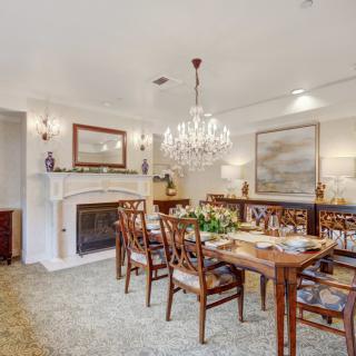 An elegant dining room with a chandelier, a beautifully set table, and a fireplace.