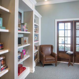 A cozy reading nook featuring a leather chair and library shelves brimming with books.
