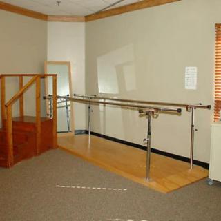 An indoor physical therapy room equipped with parallel bars and stairs for rehabilitation exercises.