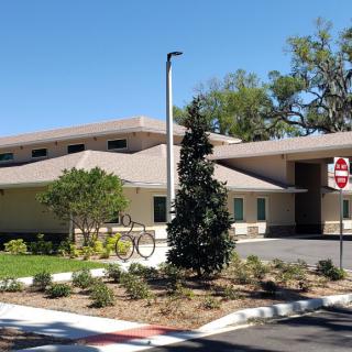 A modern residential building surrounded by trees and bushes on a sunny day.