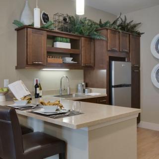 A modern kitchen with wooden cabinets, a kitchen island with seating, and stainless steel appliances.