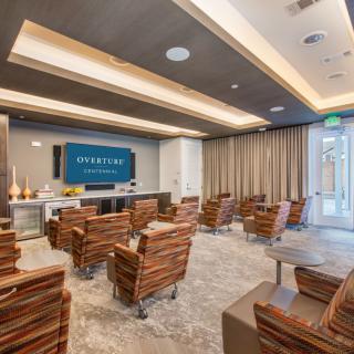 A modern conference room with theater-style seating and a large presentation screen.