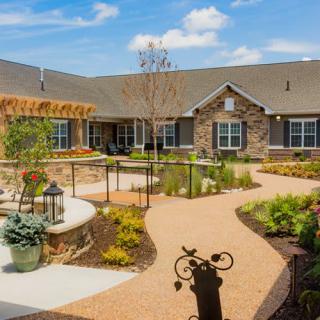 A beautifully landscaped courtyard with a path leading to a stone building under a clear blue sky.
