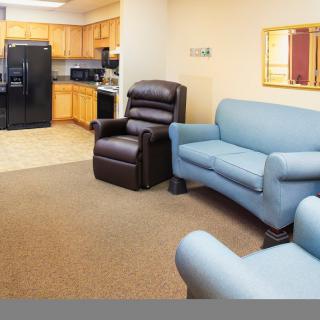 A cozy living area with a sofa, recliner, and view into a kitchen.