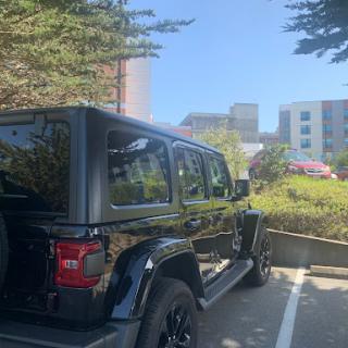 A black SUV parked in an urban area surrounded by greenery.