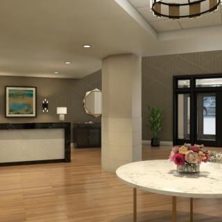 A modern lobby with a reception desk, elegant decor, and a round table with flowers.