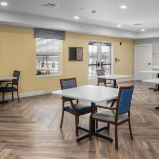 A spacious dining area with tables and chairs, featuring a wooden floor and natural lighting.