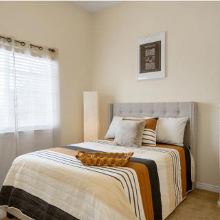 A cozy bedroom with a neatly made bed featuring striped bedding and decorative pillows.