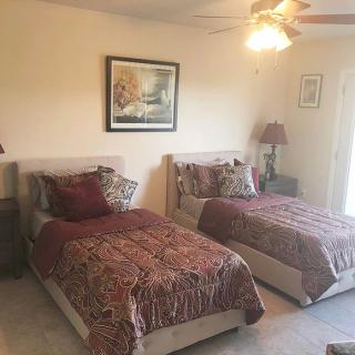 A cozy bedroom featuring two twin beds with decorative bedding and artwork on the wall.