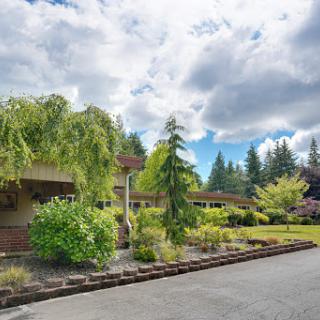 A charming residential home surrounded by lush greenery and trees under a cloudy sky.