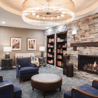 A cozy living room with a fireplace, elegant chandelier, and comfortable seating arrangement.