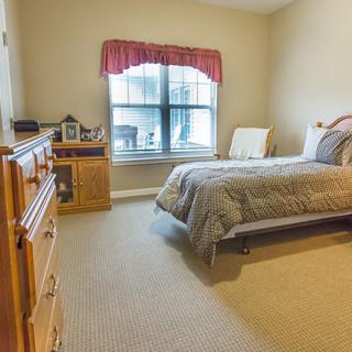 A cozy bedroom with a bed, dresser, and window with curtains.
