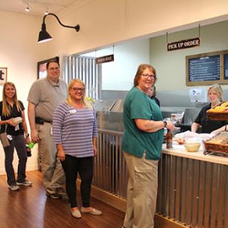 A group of people waiting in line at a cafe, ready to be served.