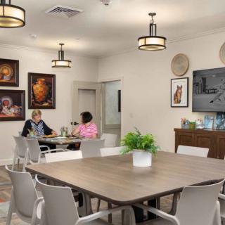 A cozy dining area with two people conversing at a table, surrounded by modern decor and artwork.