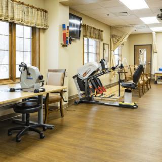A rehabilitation room with therapy equipment and seating area.