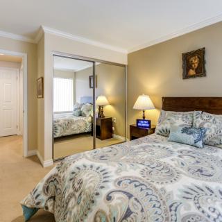 A cozy bedroom featuring a bed with patterned bedding, mirrored closet doors, and stylish decor.