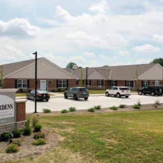 A view of a residential or commercial building with parked cars and a sign in the foreground.