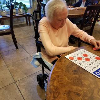 An elderly woman playing bingo at a table indoors.