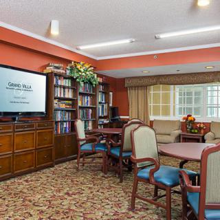 A cozy living area with bookshelves and seating arrangements, featuring a television.