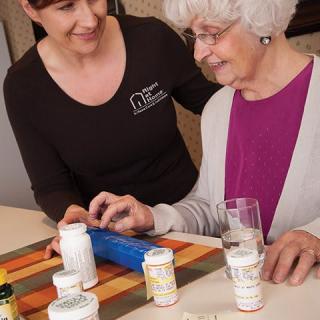 A caregiver assists an elderly woman with her medication management.