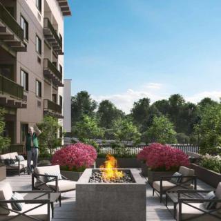 A modern apartment complex with an outdoor seating area featuring a fire pit and lush landscaping.